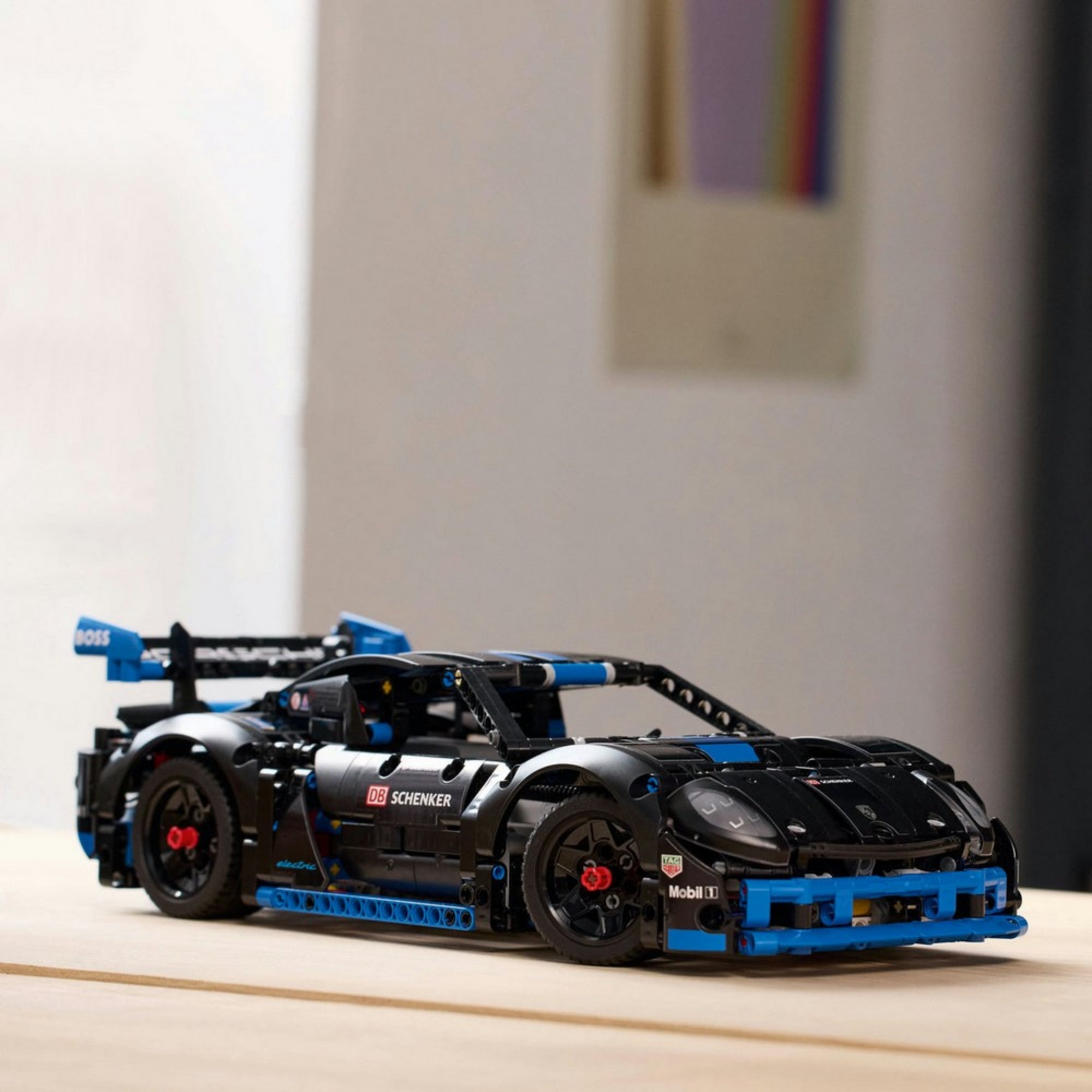 A LEGO Technic Porsche GT4 e-Performance kiállítva egy világos faasztalon, jól látható a részletes felépítése, légterelője és gumijai.