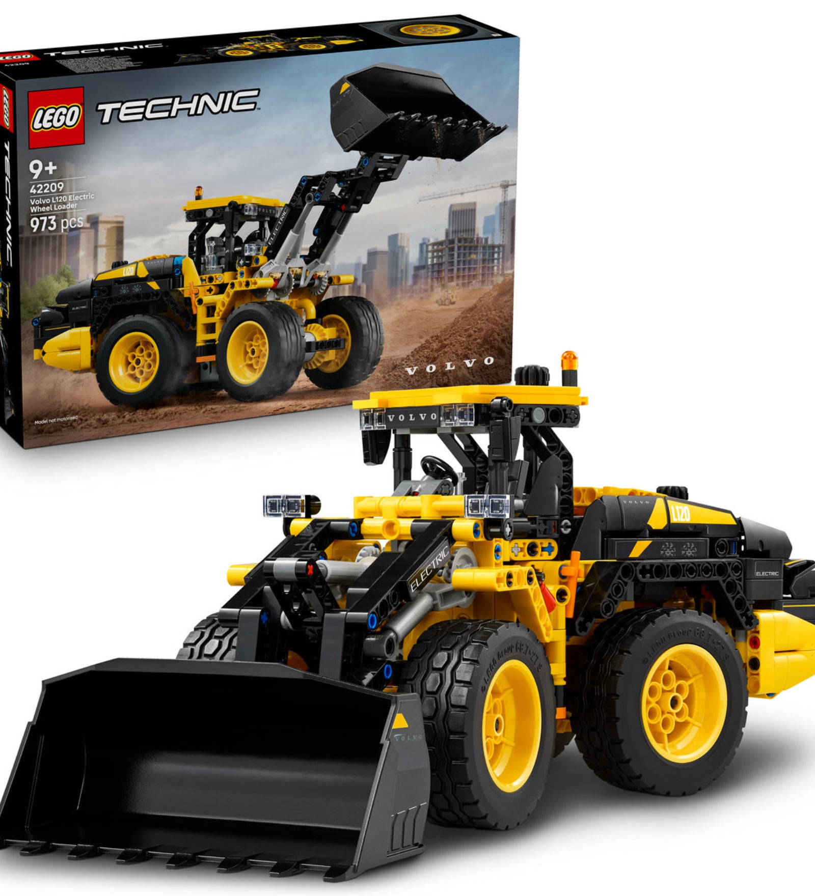 A LEGO Technic Volvo L120 Electric Wheel Loader (42209) készlet doboza és az összerakott markológép homokos terepen, városi háttérrel.