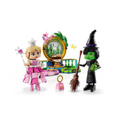 A LEGO Wicked készlet doboza és a két főszereplő, Elphaba és Glinda figurája a díszlettel, színes kiegészítőkkel és smaragdzöld háttérrel.