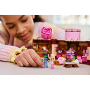 Kislány játszik a LEGO Wicked Glinda és Elphaba kollégiumi szobája (75683) készlettel, a nyitott bőrönd mellett két minifigurát fog a kezében.