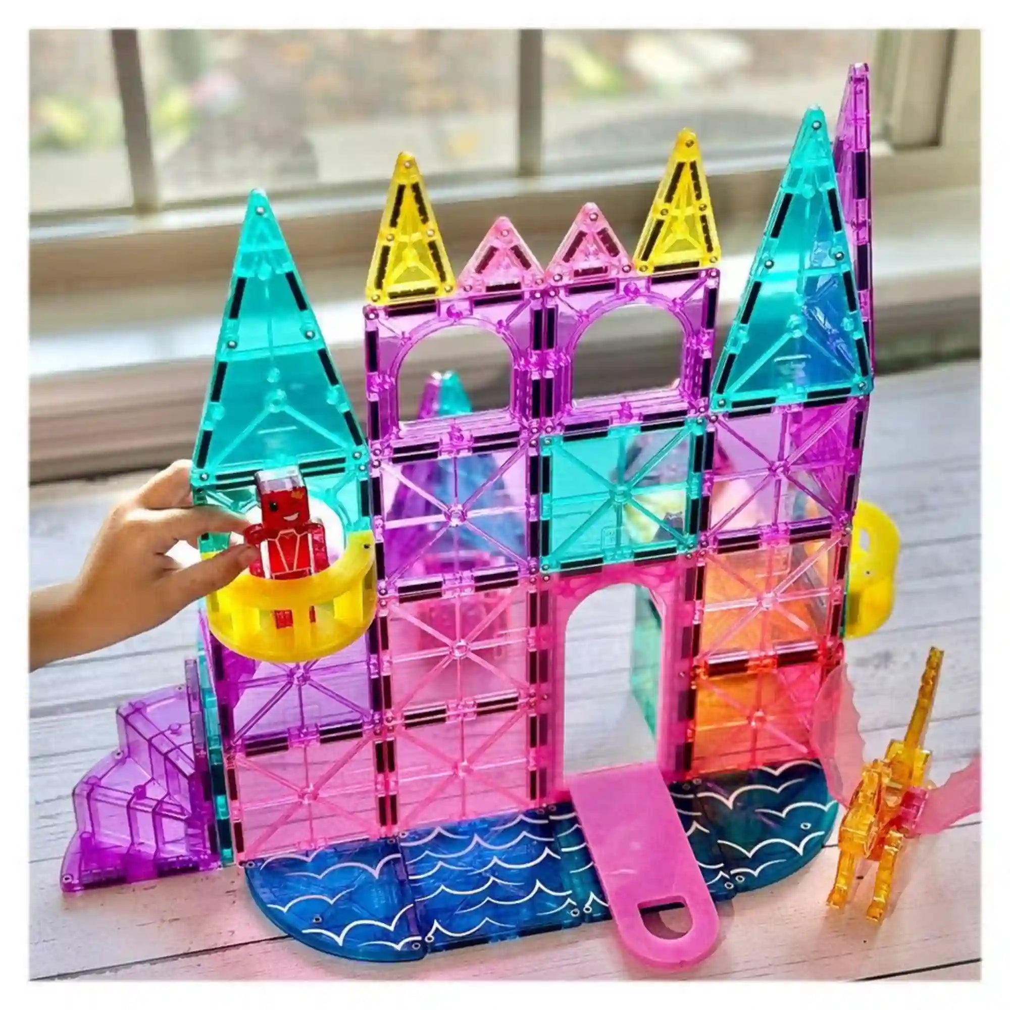 MAGNA-TILES Castle Deluxe 48 darabos építőkészlet színes, áttetsző mágneses lapokból épített kastélya, tornyokkal, erkéllyel, csúszdával és játékfigurával.