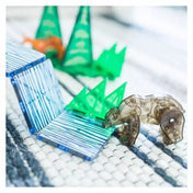 MAGNA-TILES Forest Animals mágneses építőkészlet átlátszó barna medvefigurája kék-fehér mintás mágneses lapok és zöld fenyőelemek mellett.