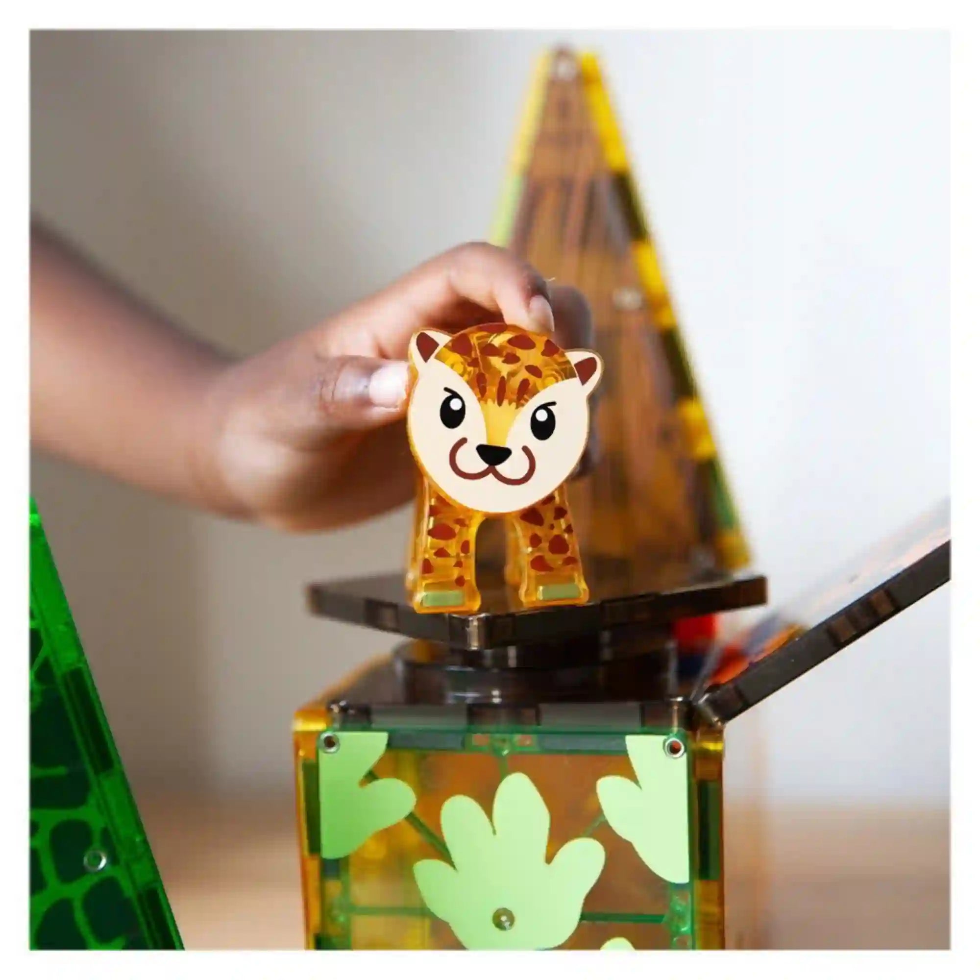 MAGNA-TILES Jungle Animals mágneses építőkészlet leopárdfigurája egy forgatható építőelemen, amelyet egy gyermek kézzel tart.