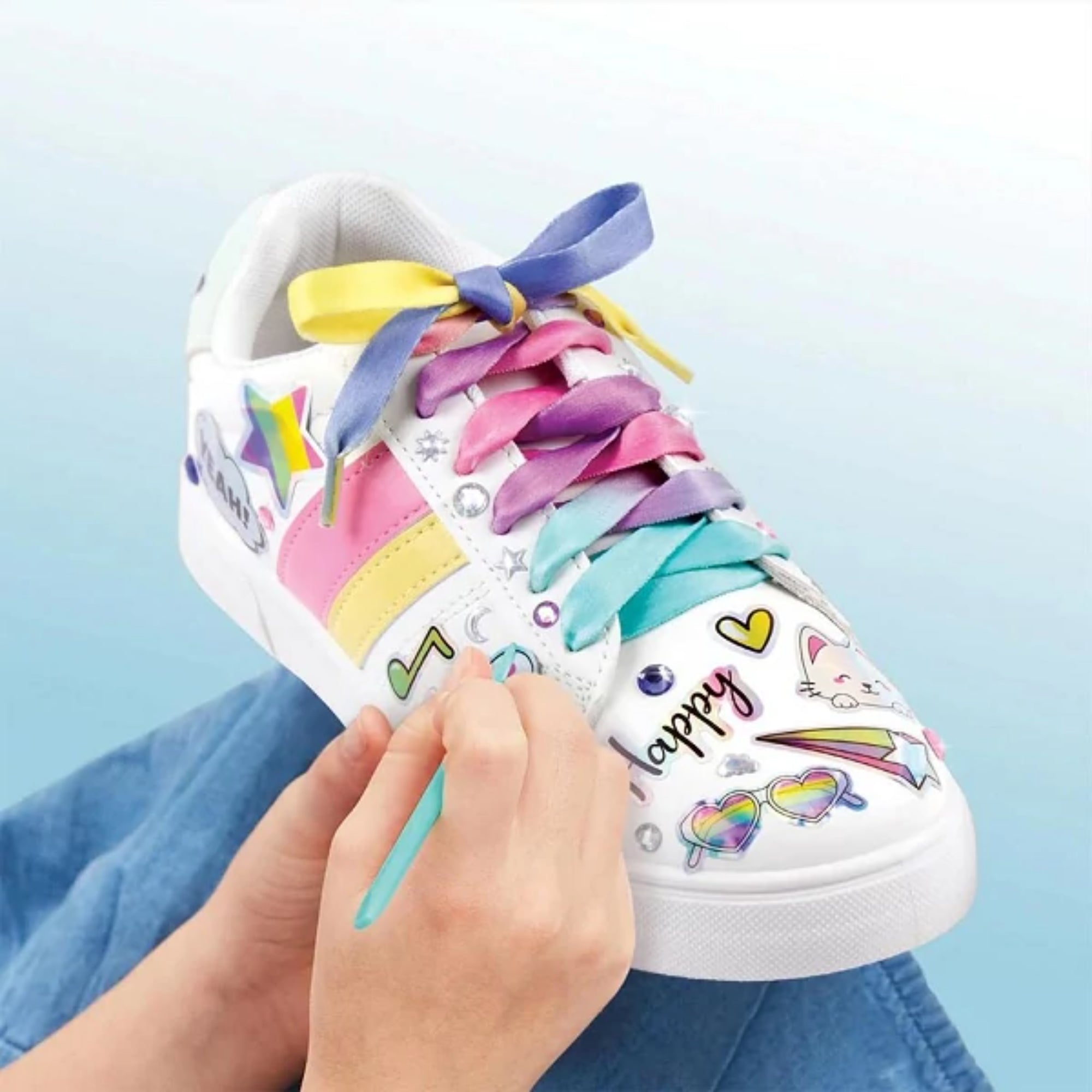 Make It Real Rainbow Street Chic cipőmatrica készlettel díszített fehér cipő, szivárványszínű fűzővel és kedves, színes mintákkal.