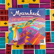 Marrakech társasjáték dobozfedél színes marokkói szőnyegmintákkal és a piac jelenetét ábrázoló illusztrációval.