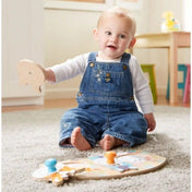 Melissa & Doug First Play farm óriás gombos puzzle használat közben, ahol egy kisgyermek a szőnyegen ülve illeszti a fa puzzle darabokat.