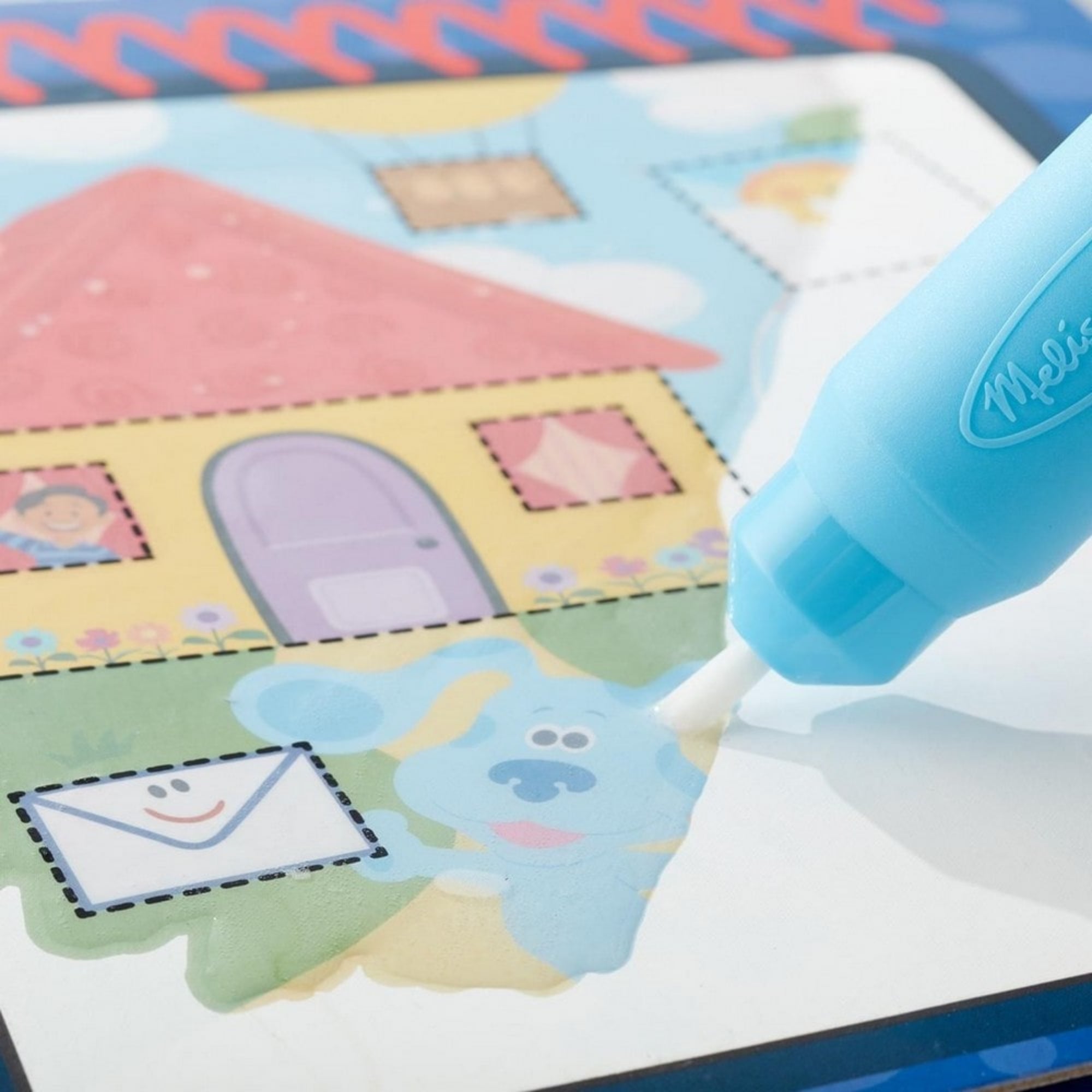 A Melissa & Doug Water WOW! – Azúrkék nyomok és te: Formák vízzel festős szett közelről, ahogy a víztollal festve megjelenik Kék kutyus és a házikó képe.