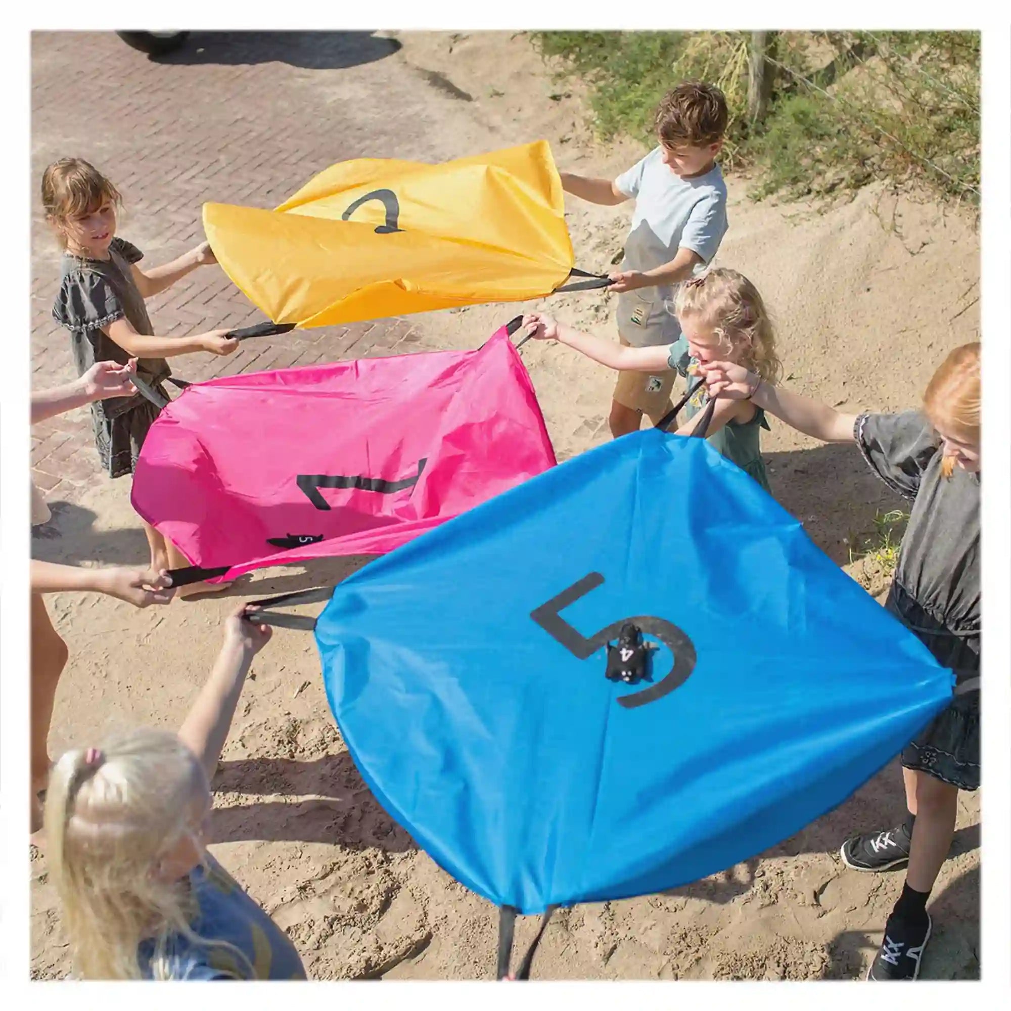 Gyerekek a BS Toys Squirrel Parachutes ügyességi játékkal játszanak, közösen mozgatva a színes ejtőernyőket.