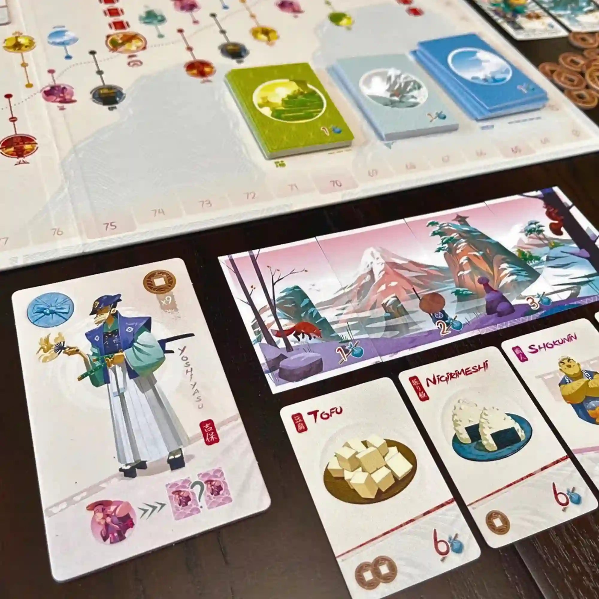 Tokaido társasjáték részlet, karakterkártyával és ételkártyákkal (tofu, nigirimeshi) japán hangulatban.