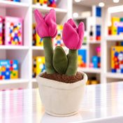Tulipános virágcserép plüssfigura két élénk rózsaszín tulipánnal, zöld szárakkal és levéllel, barna plüssfölddel és puha, fehér kaspóval.