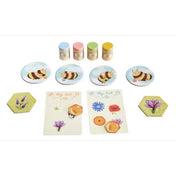 A Zümmögő társasjáték aranyos játékelemei: méhecskés korongok, színes mézesüvegek, virágos kártyák és hatszögletű mezők, amelyek a nektárgyűjtést és mézkészítést idézik.