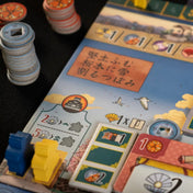 A fehér várkastély: Párbaj társasjáték táblája és zsetonjai részletes japán motívumokkal, különböző ikonokkal és színes jelölőkkel.