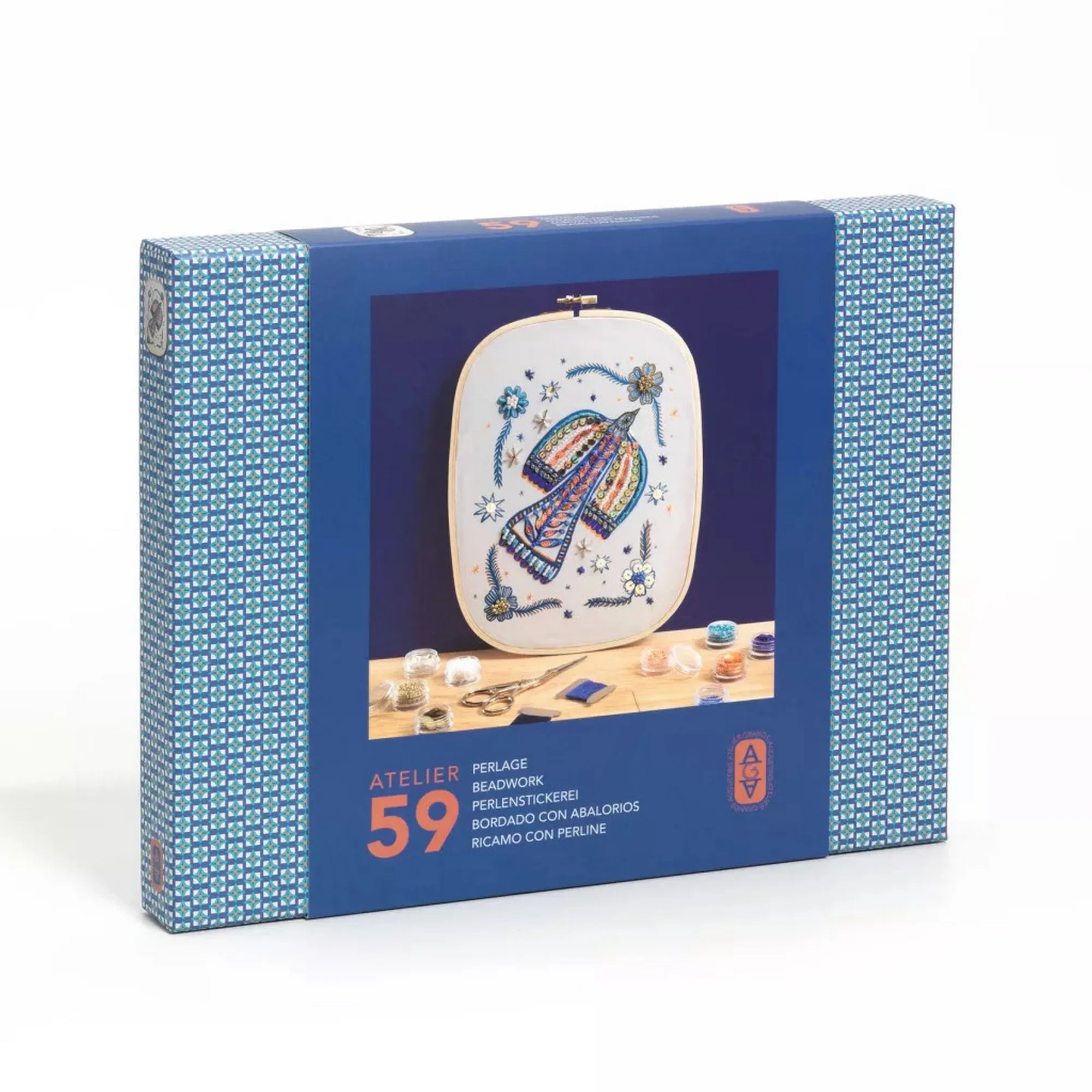 Atelier 59 hímző készlet felnőtteknek: Gyöngymadár – dobozkép: A készlet kék doboza a gyöngyökkel díszített, színes madármintás hímzéssel a középen, körülötte gyöngyök és fonalak.