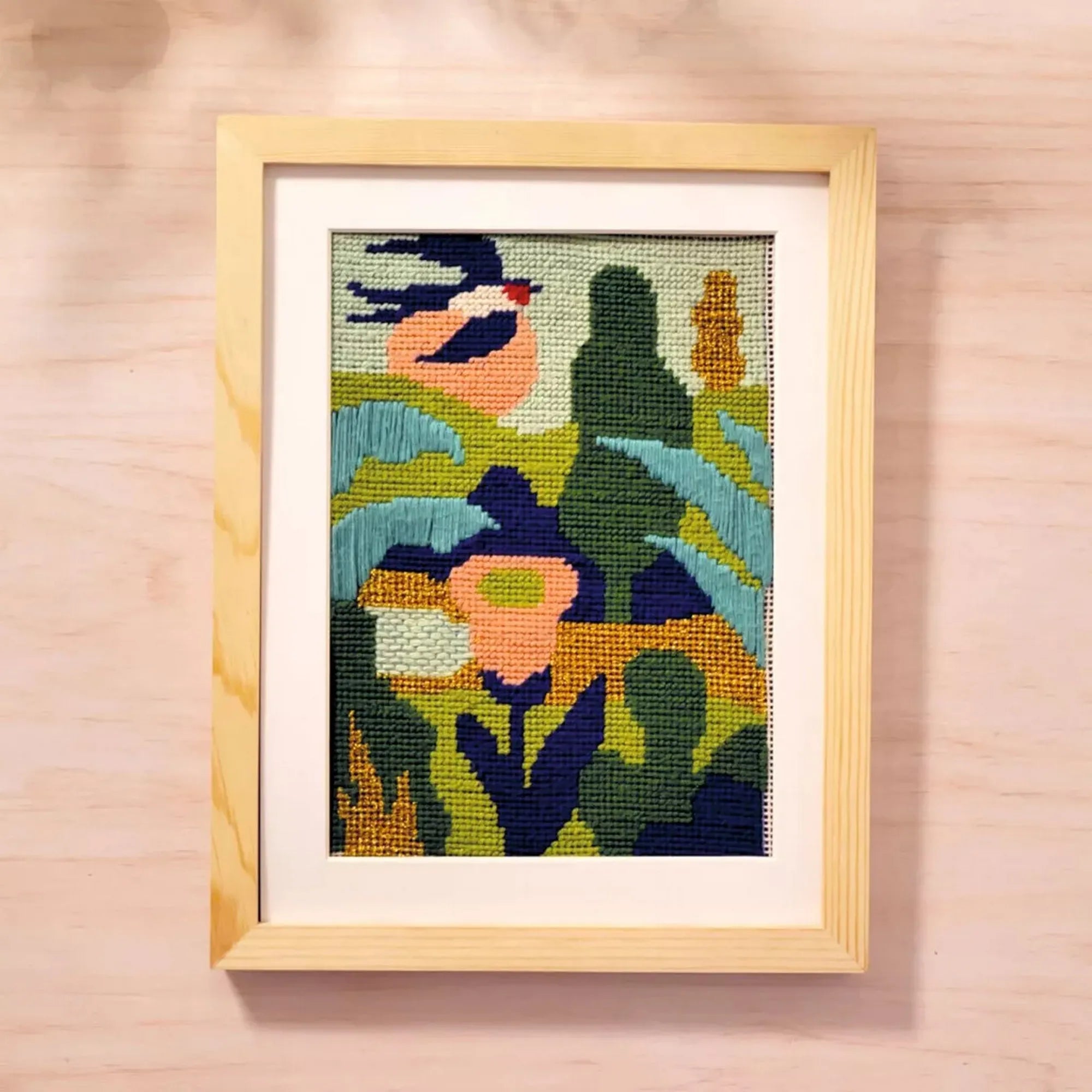 Atelier 65 hímzőkészlet – élénk színekkel készült, absztrakt növényi mintát ábrázoló kész hímzés világos fa keretben.