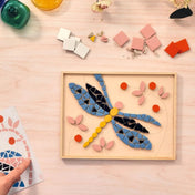 Atelier 72 mozaikkészítő felnőtteknek: Szitakötő – színes mozaiklapokból kirakott szitakötő mintakép fa keretben, felülnézetből.