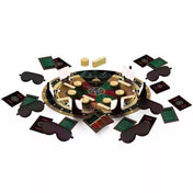 A The Traitors – Az Árulók társasjáték kiterített tartozékai: középen a kör alakú játéktábla, körülötte fekete szemkötők, zöld és piros kártyák, aranyrúd jelzők és játékelemek. A játék hangulata a kastélybeli árulás és titkos szerepek izgalmát idézi.