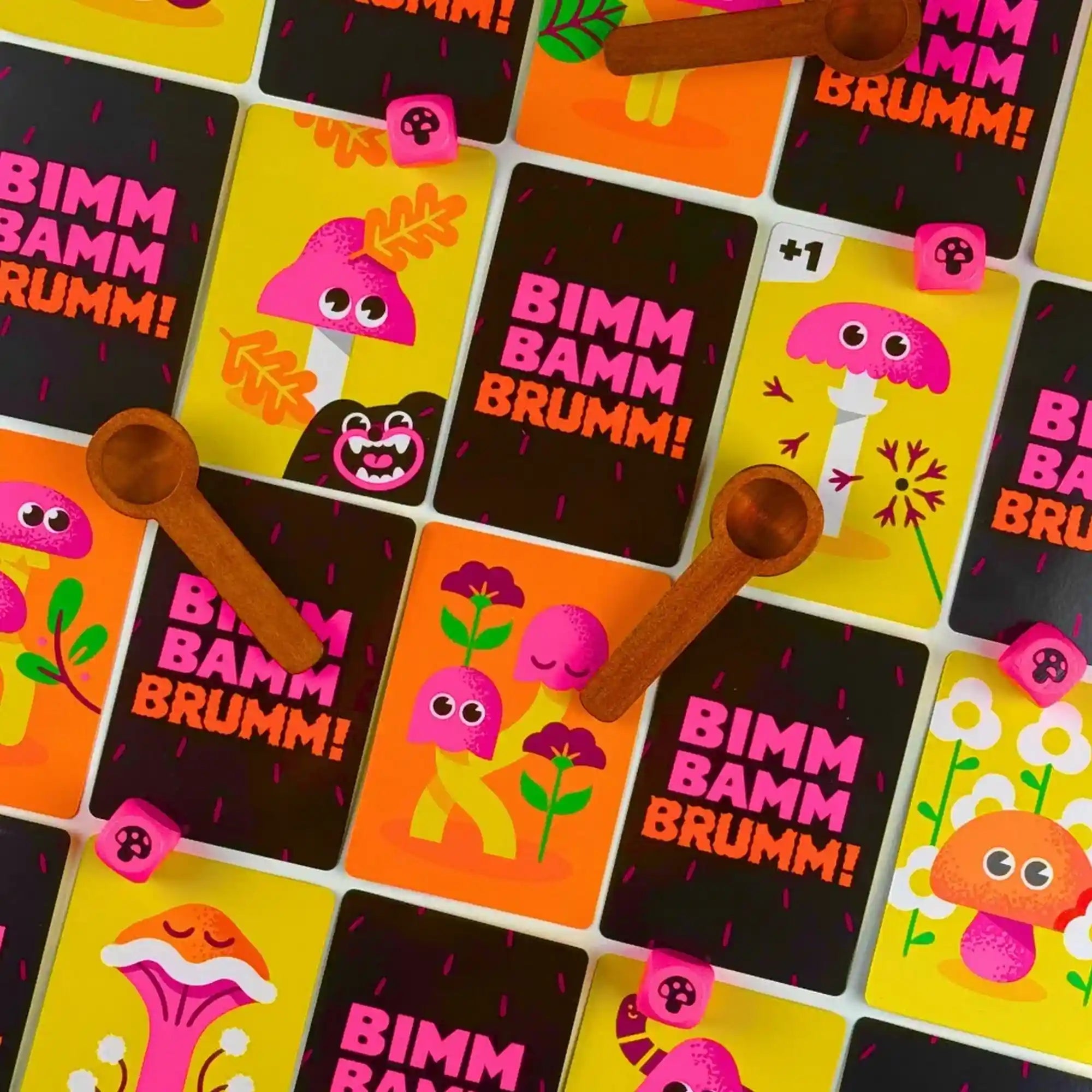Színes gombás kártyák, fakanalak és rózsaszín dobókockák a Bimm Bamm Brumm! gyors partijáték játékmenete közben.