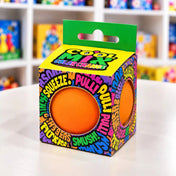 Cool Mix Squishy 7 cm stresszlevezető játék (narancssárga) – Narancssárga squishy labda színes mintázatú dobozban, elöl és oldalt kör alakú nyílással.