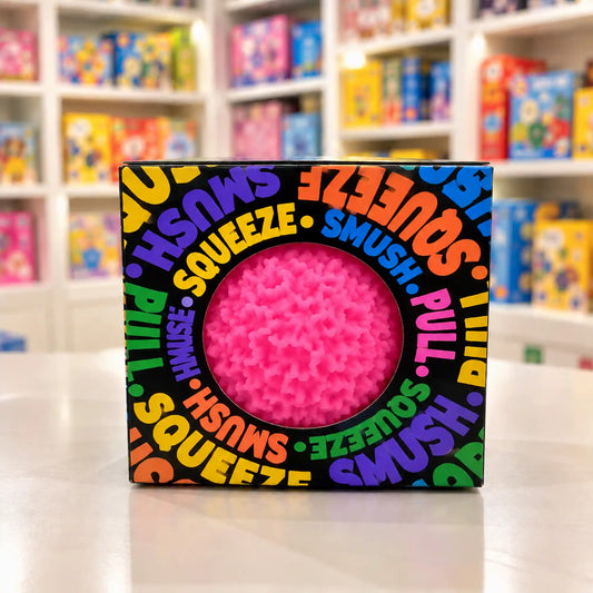 Cool Mix Squishy: Bolyhos tapintású labda 6 cm stresszlevezető játék (rózsaszín), fekete, színes feliratokkal díszített dobozban, kerek ablakon keresztül látható.