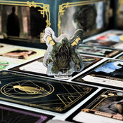 Cthulhu karton figura műanyag talpban, szörny ábrázolás kártyák és játékelemek között