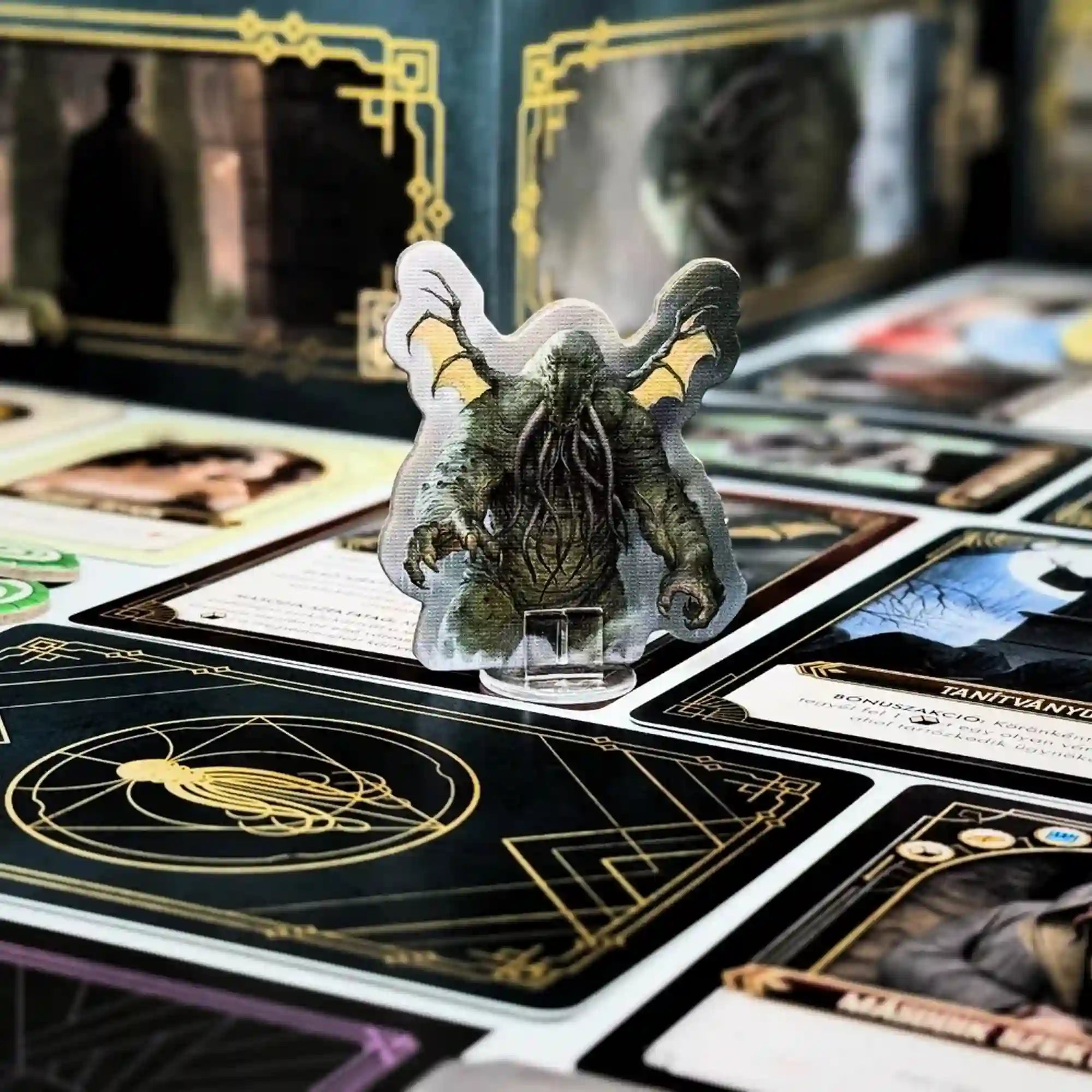 Cthulhu karton figura műanyag talpban, szörny ábrázolás kártyák és játékelemek között