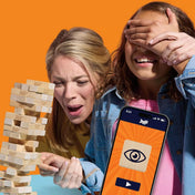 „Két játékos izgatott arccal figyeli a Jenga tornyot játék közben, a telefonon Jenga alkalmazás jelenik meg.”