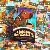 Kapibarista magyar nyelvű társasjáték doboza kártyák hátterében, színes játékkomponensekkel.