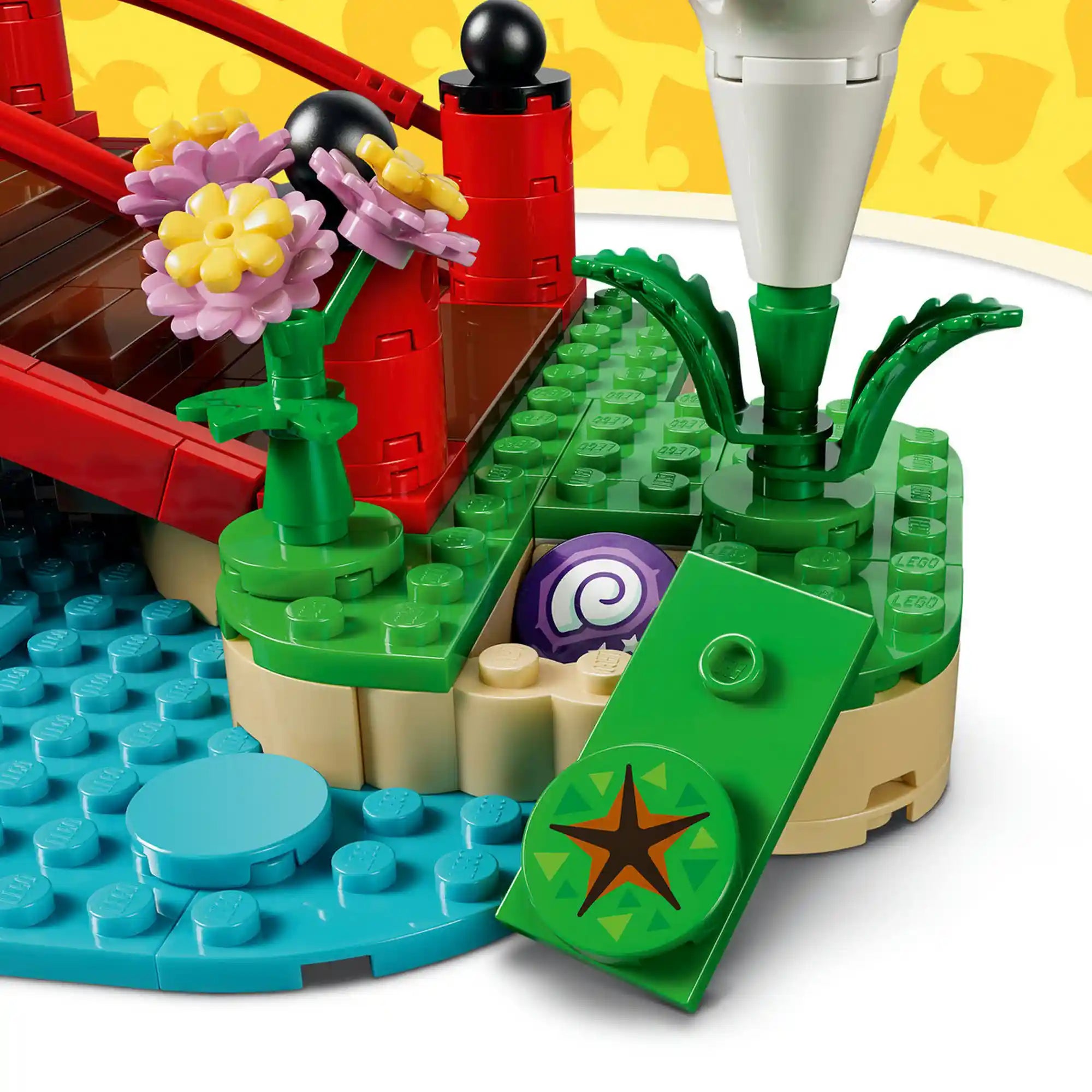 Közeli részlet a LEGO Animal Crossing: Timmy és Tommy vidám kirándulása 77059 készlet rejtett földdarabjáról, amely felnyitható, és egy elrejtett kövületet rejt a virágok és a tópart mellett.