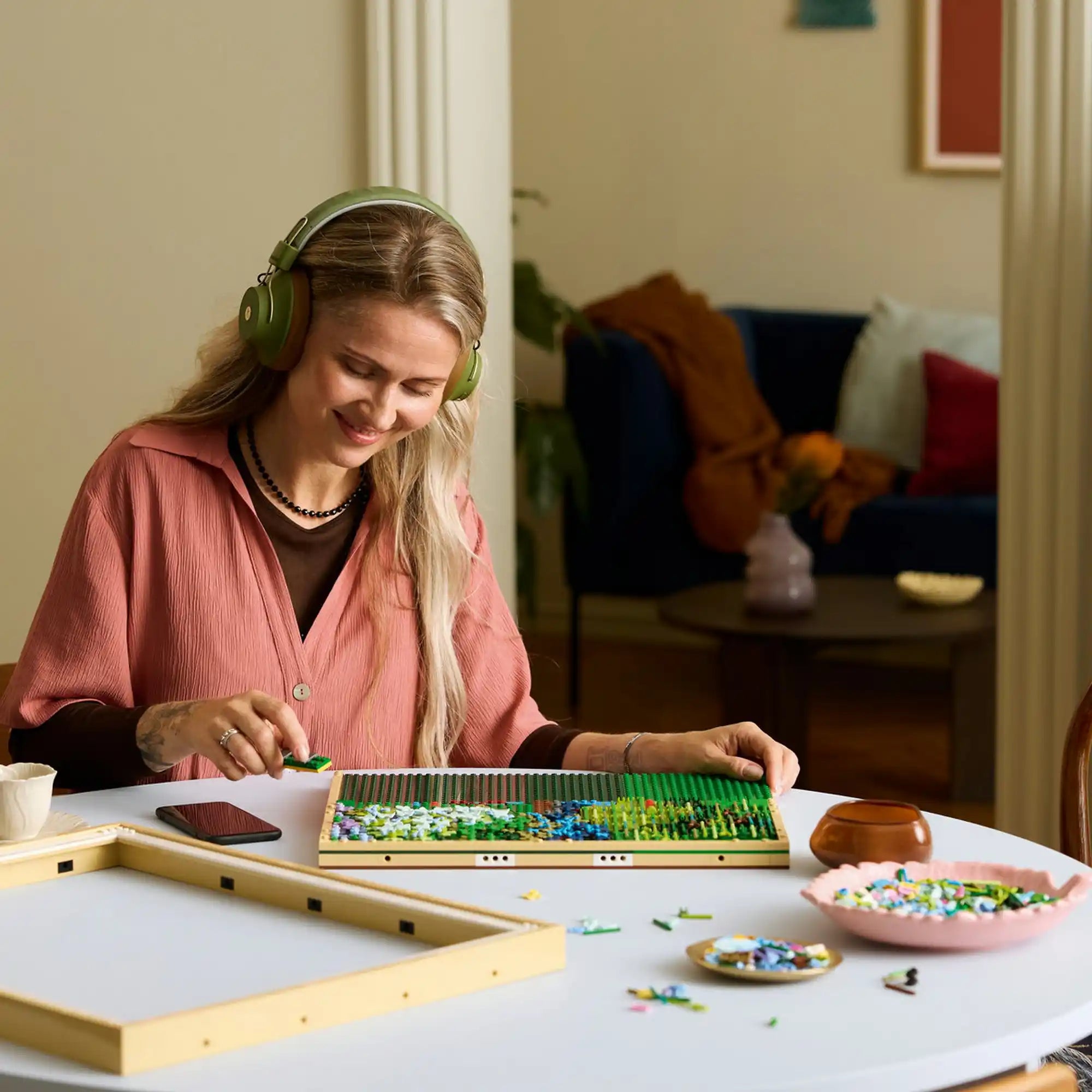 LEGO Art: Claude Monet Híd a vízililiomos tó felett 31220, 3179 darabos építés közben, nő összeállítja a mozaik képet asztalon.