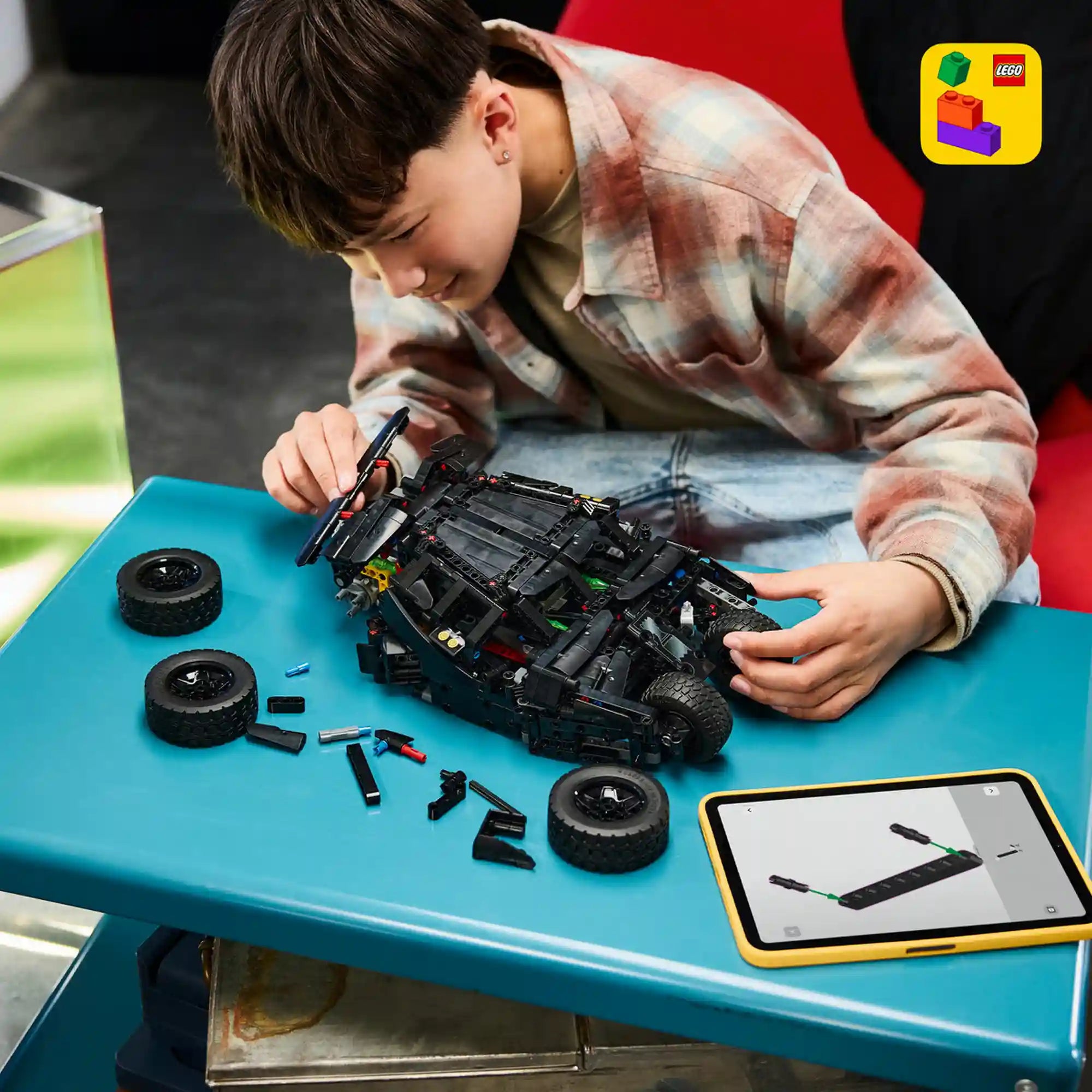 Gyermek a LEGO Builder alkalmazás segítségével építi a LEGO Technic Batmobile Tumbler 42239 modellt.