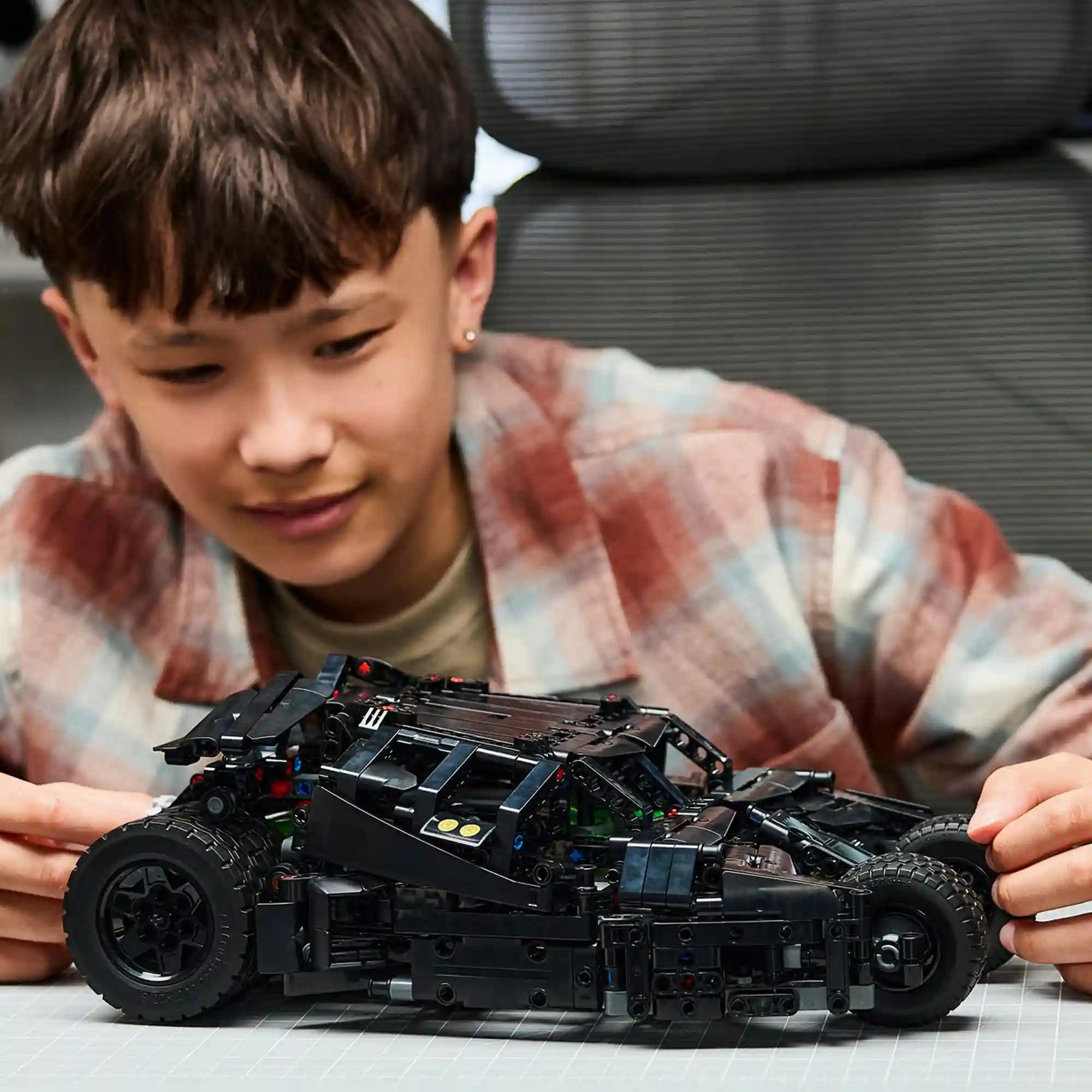 Gyermek a megépített LEGO Technic Batmobile Tumbler 42239 modellt vizsgálja építés után.