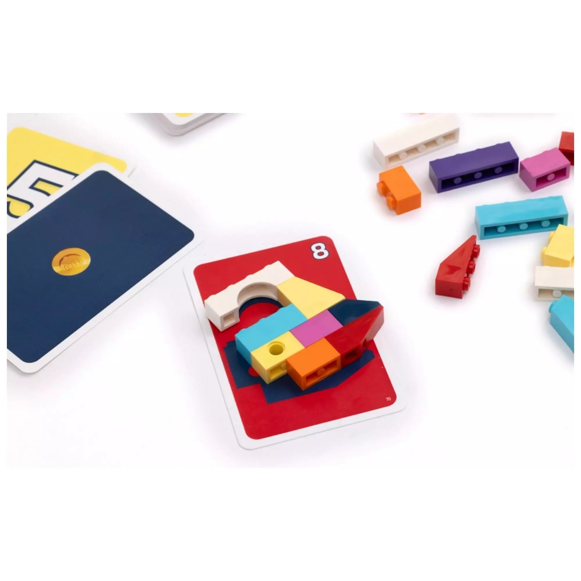 „LEGO Brick Like This társasjáték piros kártyára épített LEGO modellje, körülötte szétszórt építőelemek a játék közben.”