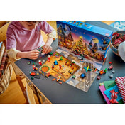 Gyermek építi a LEGO City: Adventi naptár 2026, 60510 apró karácsonyi modelljeit a kinyitott adventi naptár előtt.
