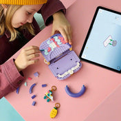Gyermek építi és testre szabja a LEGO Creator Dekorálható táska modellt, miközben a LEGO Builder alkalmazás digitális útmutatóját használja egy tableten.
