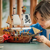 Gyermek izgatottan játszik a LEGO Creator 3 az 1-ben Ikonikus kalózhajó (31387) fő modelljével. A részletgazdag hajón kalóz minifigurák, ágyúk, vitorlák és egy vörös tengeri szörny is helyet kapott.