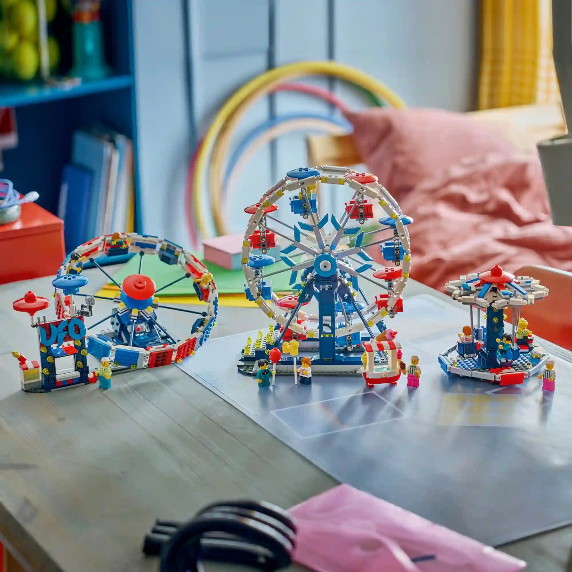 A LEGO Creator Ikonikus óriáskerék (31389) készlet mindhárom megépíthető változata egy asztalon. A képen az óriáskerék, az UFO-körhinta és a láncos körhinta látható minifigurákkal és vidámparki kiegészítőkkel.