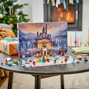 A LEGO Disney adventi naptár kinyitva az asztalon, havas kastélyháttérrel, hercegnőkkel, karácsonyfával és ajándékokkal.