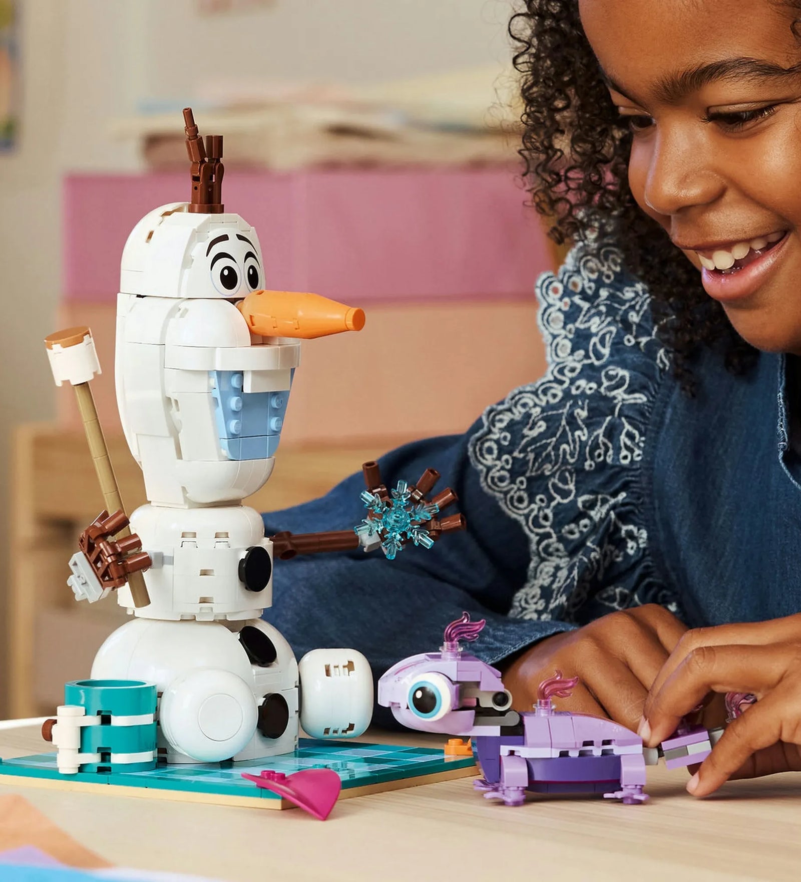 LEGO Disney: Olaf és Bruni vidám piknikezése 43287 – Gyerek játék közben Olaf és Bruni megépített figuráival az asztalon.