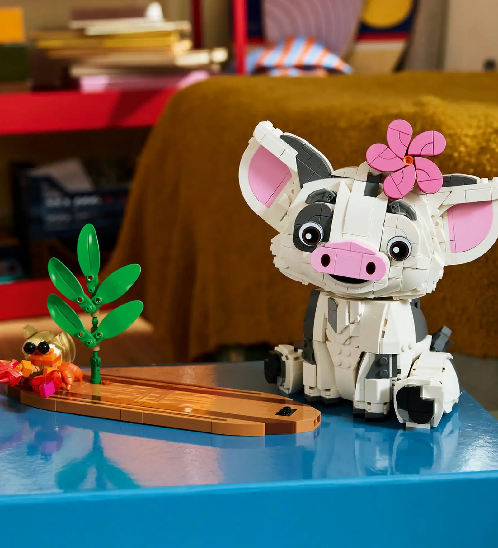 LEGO Disney: Pua 43292, 885 darabos készlet megépített Pua figurája trópusi talapzaton, pálmalevelekkel, virággal és egy kis rák figurával, dekoratív kiállítási környezetben.