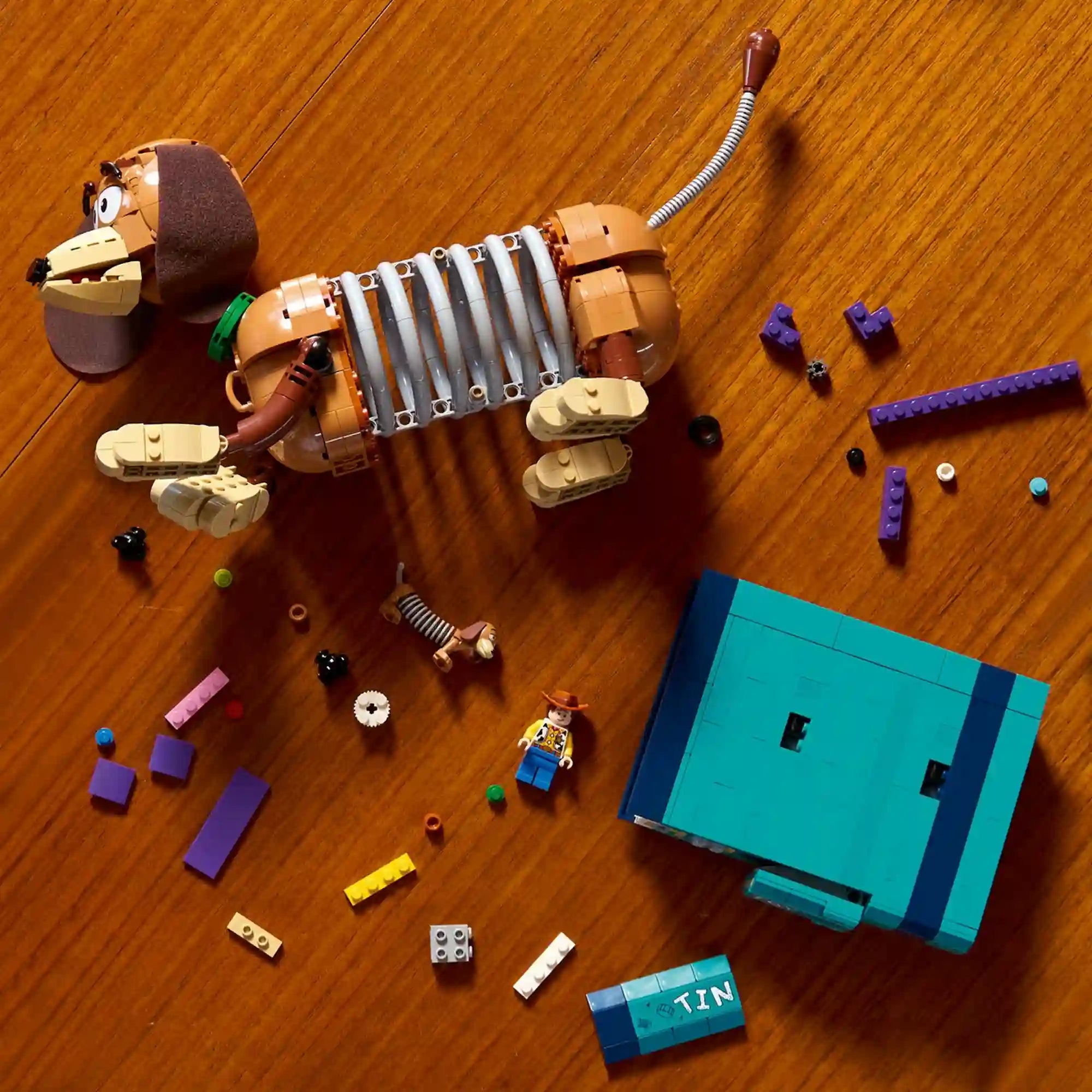 LEGO Disney: Toy Story: Slinky kutya könyvtámasz 43301, 1311 darabos – szétszedett készlet elemei és figura fa felületen.