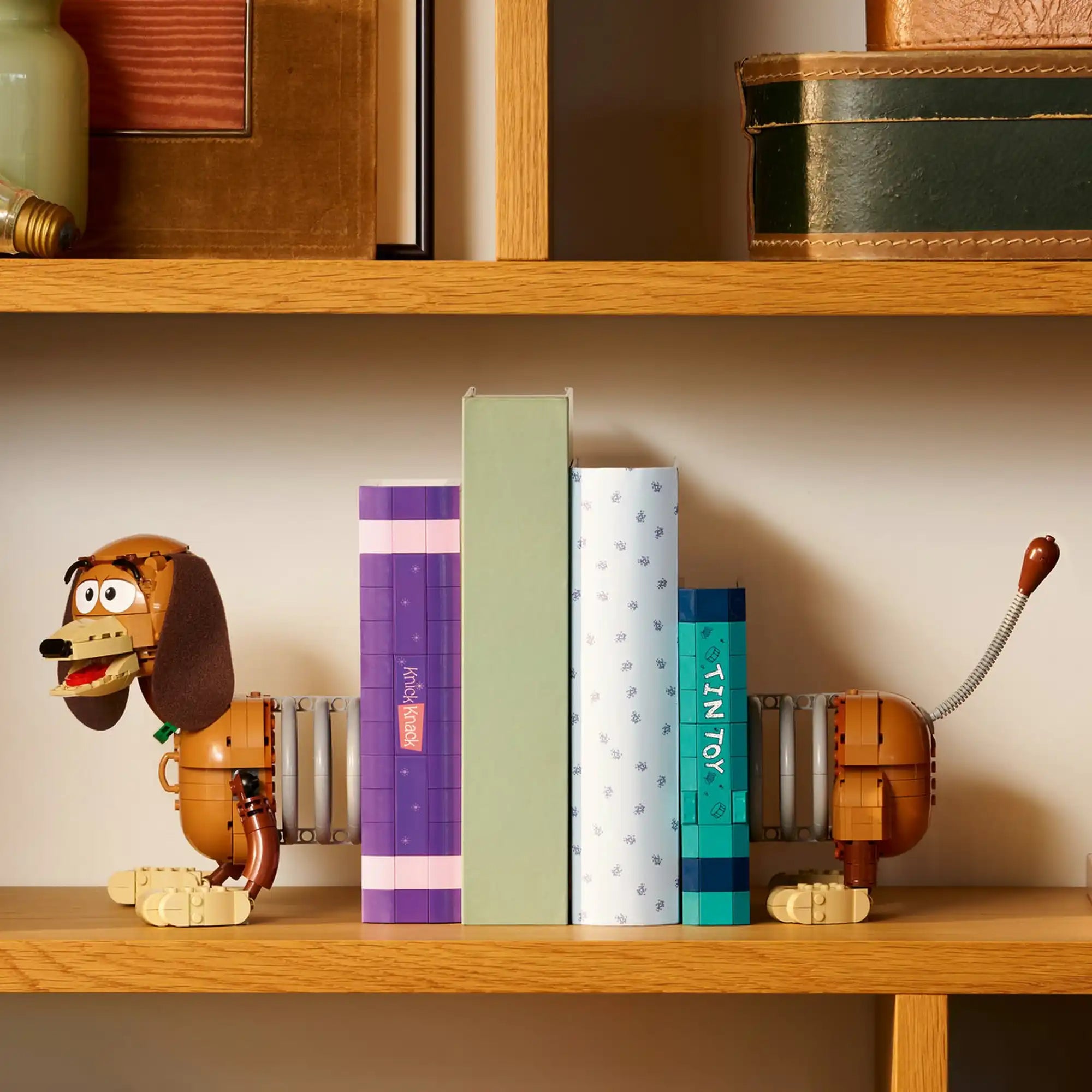 LEGO Disney: Toy Story: Slinky kutya könyvtámasz 43301, 1311 darabos – polcon elhelyezett Slinky kutya könyvtámasz könyvek között dekorációként.