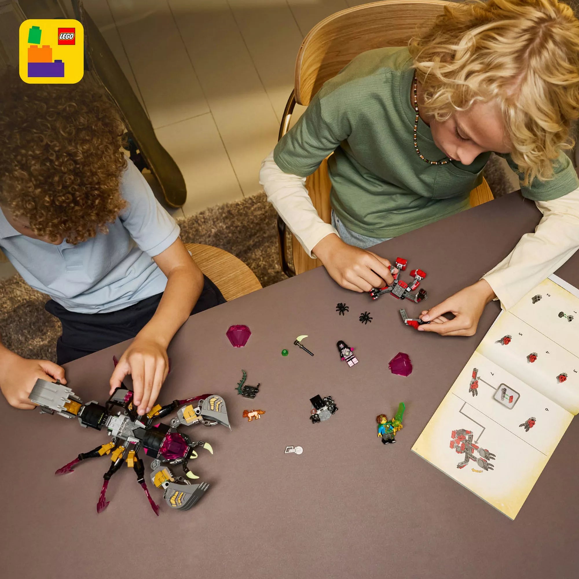 Felülnézeti kép a LEGO DREAMZzz Nightmare Scorpion Digger építéséről, szétszórt elemekkel, minifigurákkal és a nyitott építési útmutatóval.