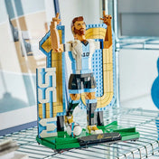 LEGO Lionel Messi – Futball-legenda (43015) kész kiállítási modell modern polcon elhelyezve, Messi győzelmi pózával, focilabdával és aranyszínű 10-es háttérelemmel.