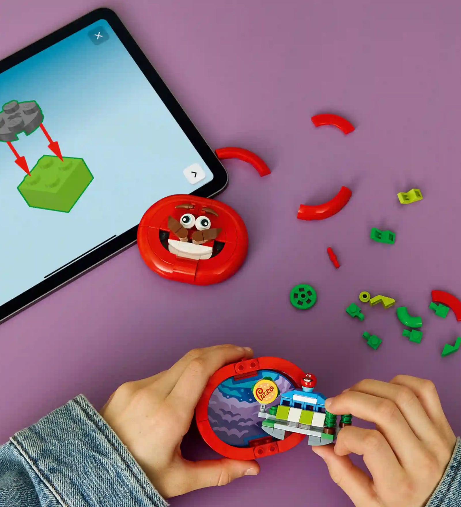 A LEGO Builder alkalmazás digitális útmutatója mellett épülő LEGO Fortnite Tomatohead modell, nyitható belső térrel és pizzéria jelenettel.