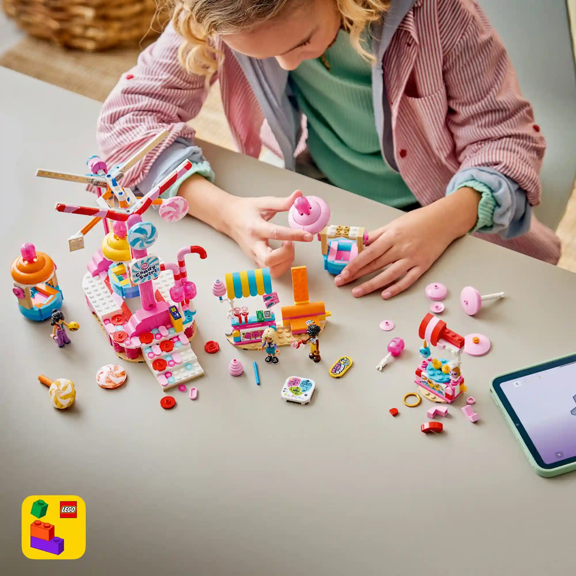 LEGO Friends: Cukorkával és muffinnal díszített óriáskerék 42700, 602 darabos készlet játék közben, ahol egy gyermek az óriáskereket és az édességes attrakciókat építi és használja.