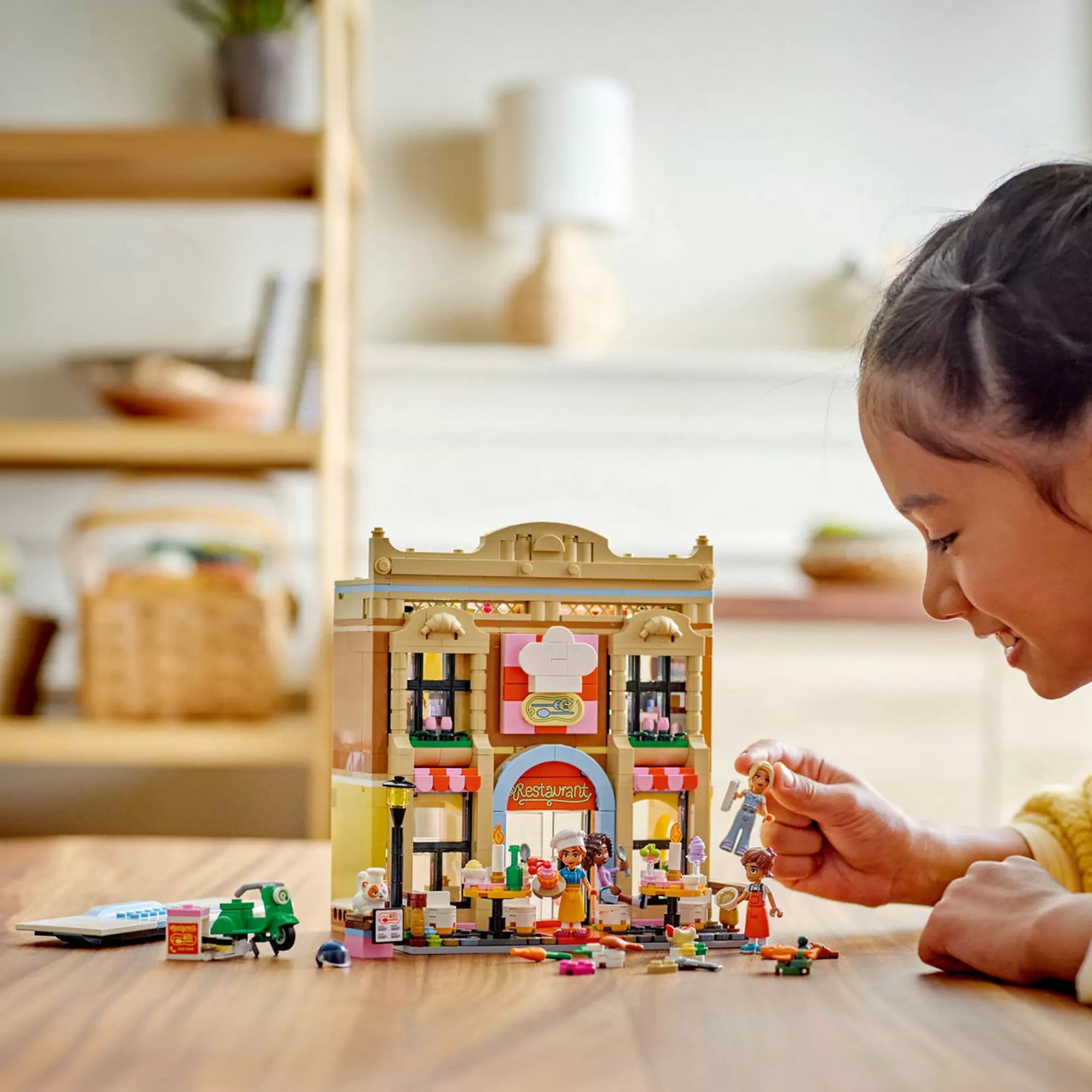  Egy kislány örömmel játszik a LEGO Friends Étterem és főzőiskola 42655 készlettel, felfedezve a részleteket.