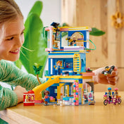 Gyermek LEGO Friends Heartlake City barátságklub készlettel játszik, a klubépületnél, minibabafigurákkal, csúszdával, drónnal és szerepjáték jelenettel.