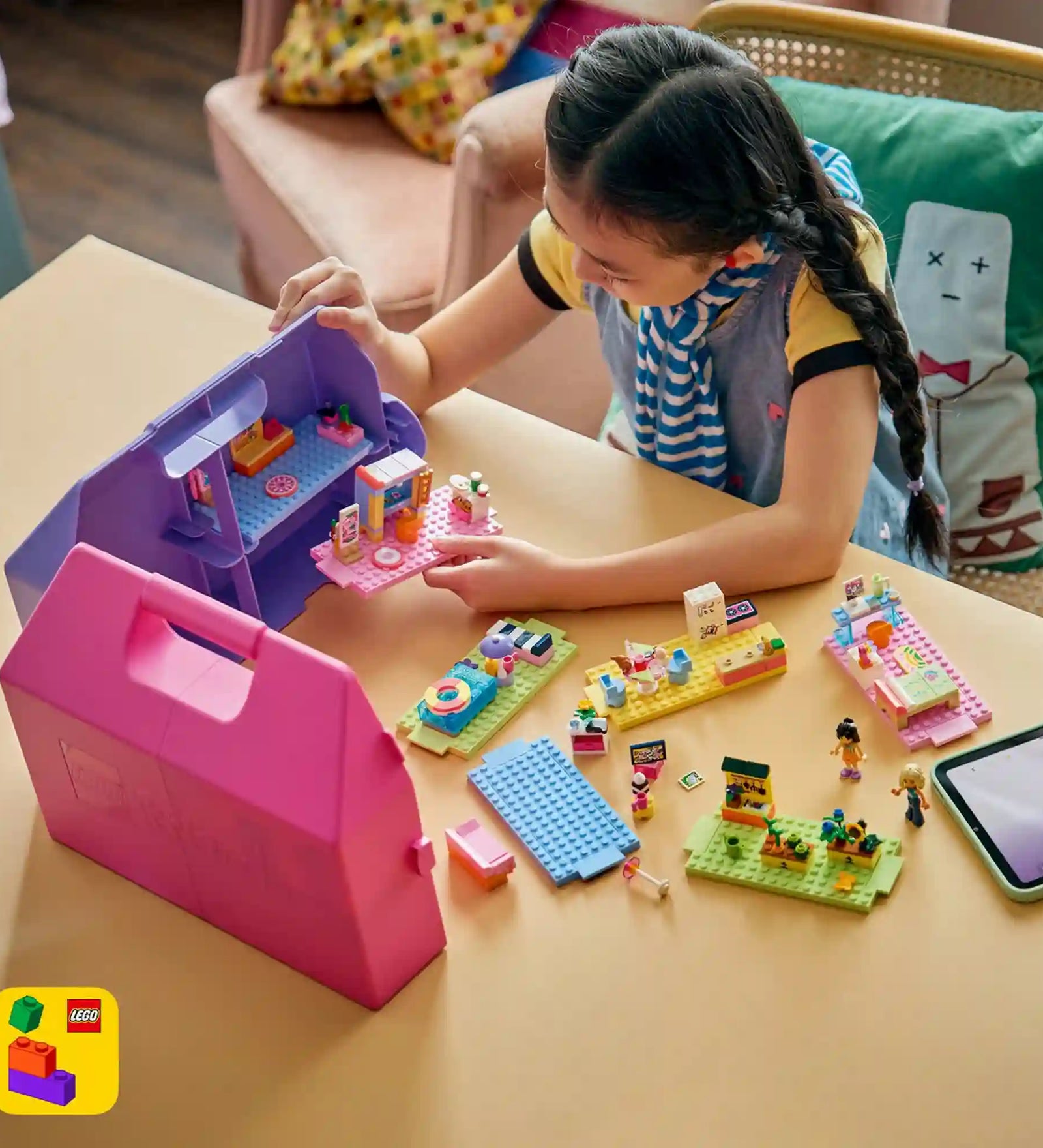 Gyermek játszik a LEGO Friends Kreatív, bőröndalakú babaház készlettel, miközben különböző szobákat rendez be és történeteket alkot.