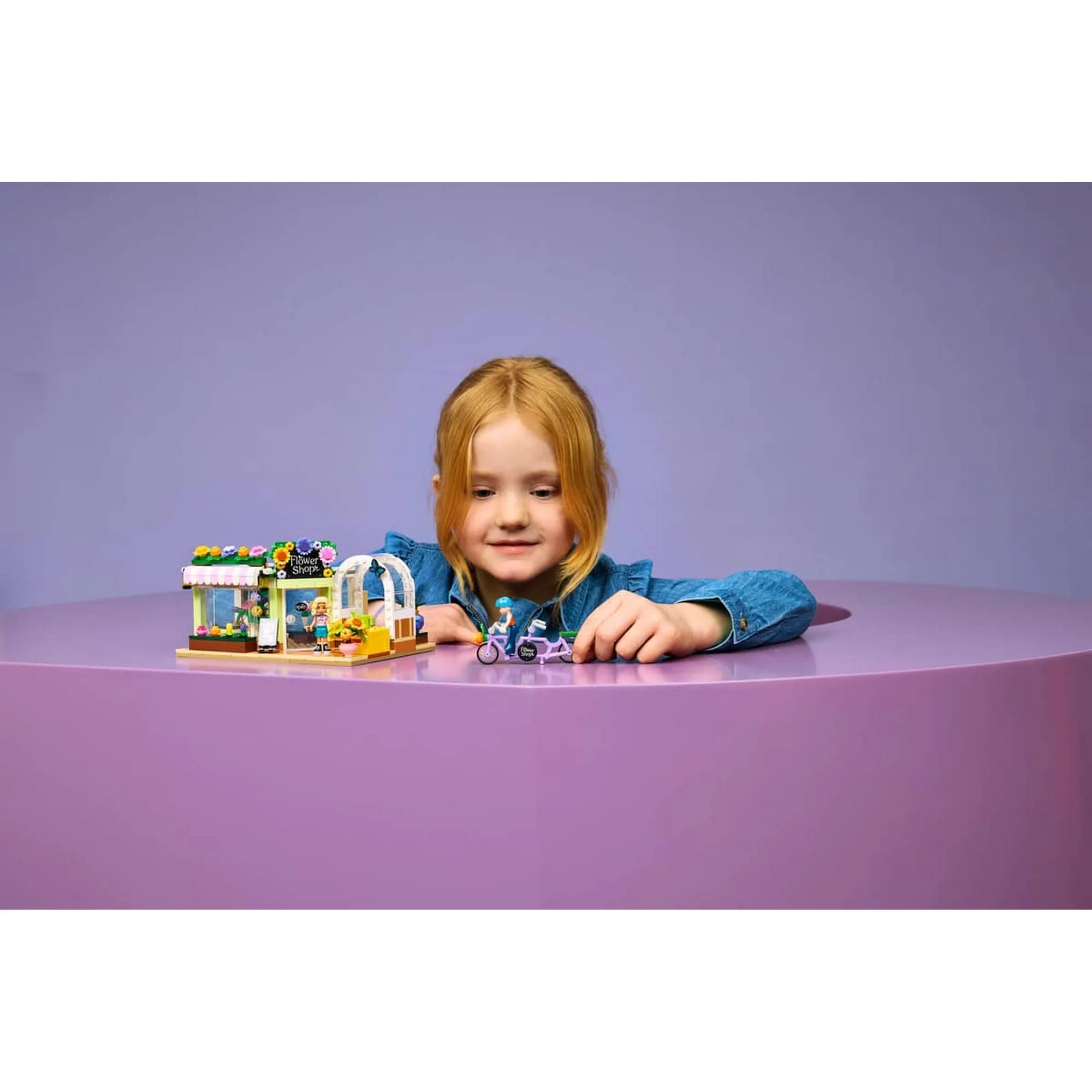Gyermek a LEGO Friends Kreatív virágbolt készlettel játszik, miközben a virágüzlet és a tandemkerékpár történeteit eleveníti meg.