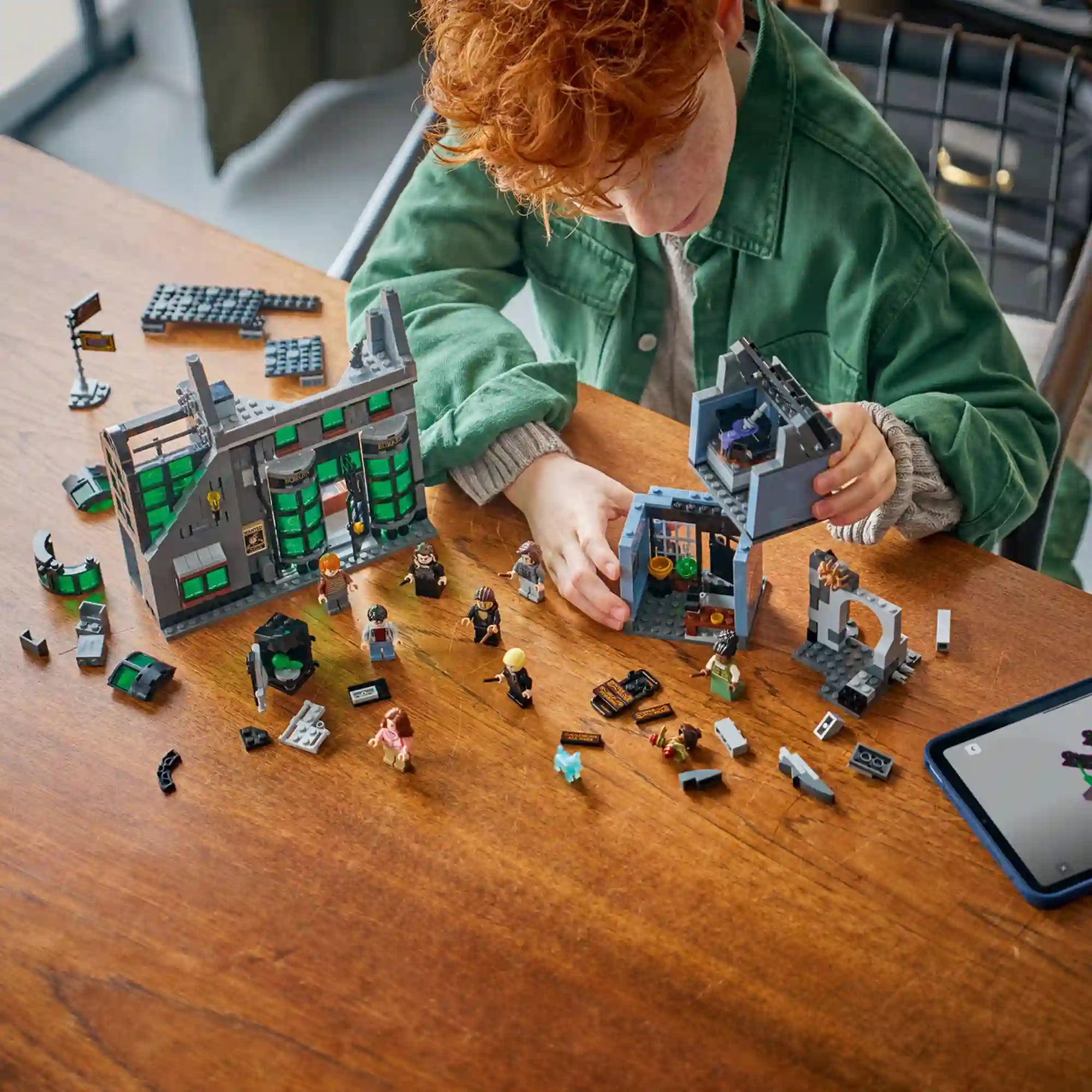 LEGO Harry Potter 76471 építési jelenet vörös hajú gyermekkel, aki a Borgin és Burkes és az Üstbolt moduljait szereli össze.